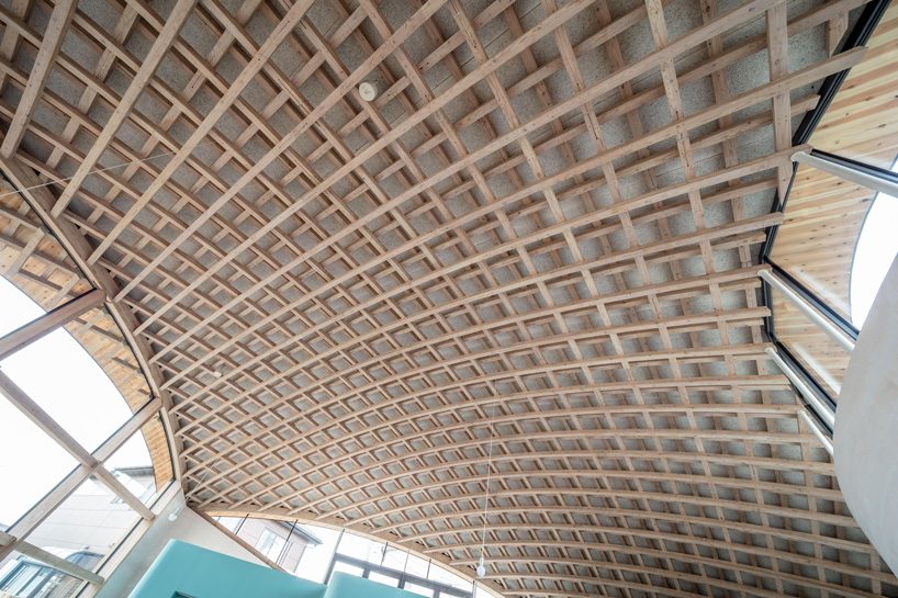 curved wood lattice roof hangs above nasca's blue sky nursery school in japan - 10