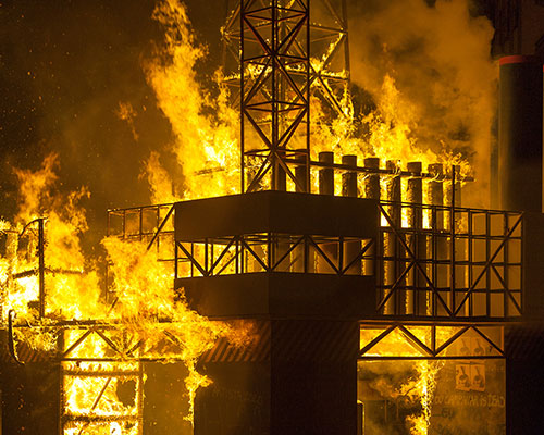 a cardboard oil rig burns to the ground in the center of valencia