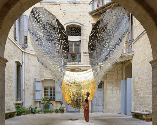 designers suspend parametric golden butterfly within a historic courtyard in montpellier