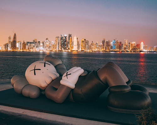 KAWS debuts inflatable sculpture on doha's dhow harbor overlooking the city skyline