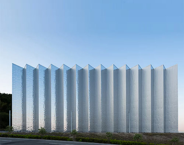 the massive steel frame is wrapped in a skin of silvery material, which