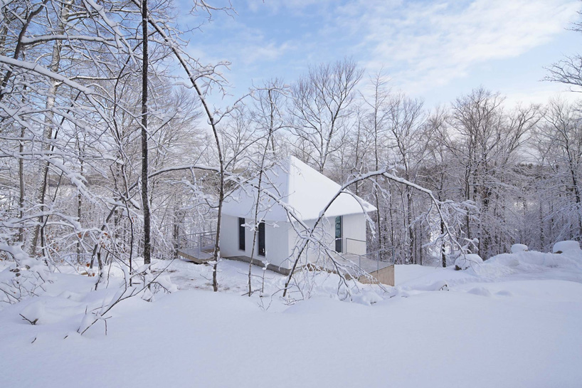 naturehumaine sets monochrome 'poisson blanc' cabin within forest in canada