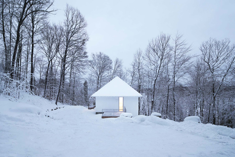 naturehumaine sets monochrome 'poisson blanc' cabin within forest in canada