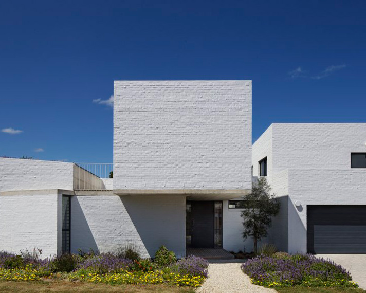 swansilva's white brick house in south africa emerges through indigenous vegetation
