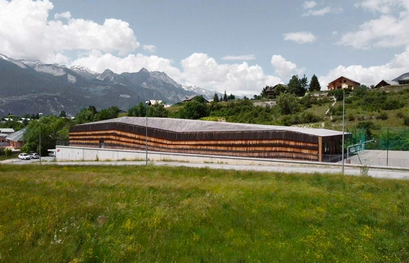 larch cladding folds over gymnasium guillestre to echo the landscape designboom