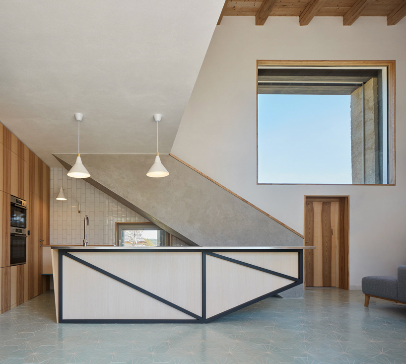 a modern kitchen island completes the geometric composition of the stairs and large window