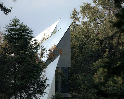 futuristic reflective cabins with pointy roofs emerge from dense forest in china