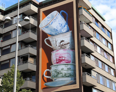 fragile teacups tumble out of a building in leon keer's ‘shattering’ 3D mural in sweden