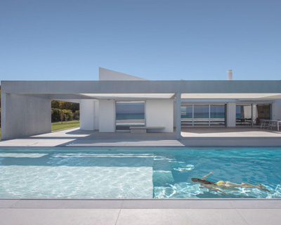 r.c. tech's white monolithic beach house sits by the coast of northern peloponnese, greece