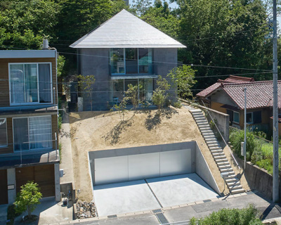 airhouse tops house on a sloping hill in seto, japan, with pyramid hip roof