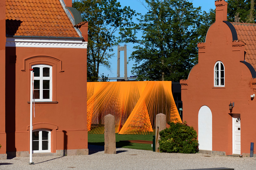 behin ha's bright orange, mesh fabric installation between buildings in denmark