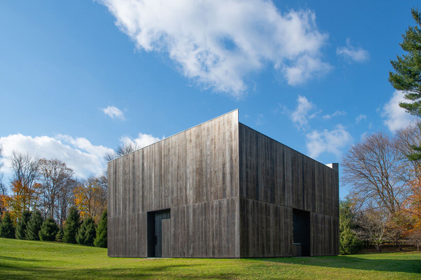 OLI architecture sets richard serra's london cross sculpture in charred wood pavilion in NY