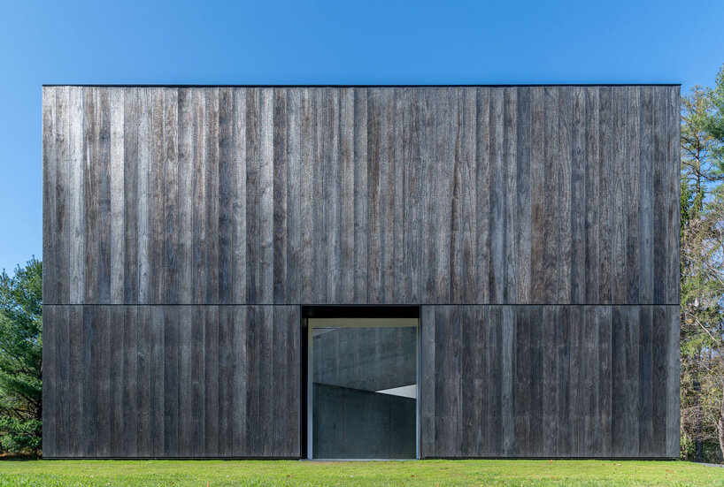 OLI architecture sets richard serra's london cross sculpture in charred wood pavilion in NY