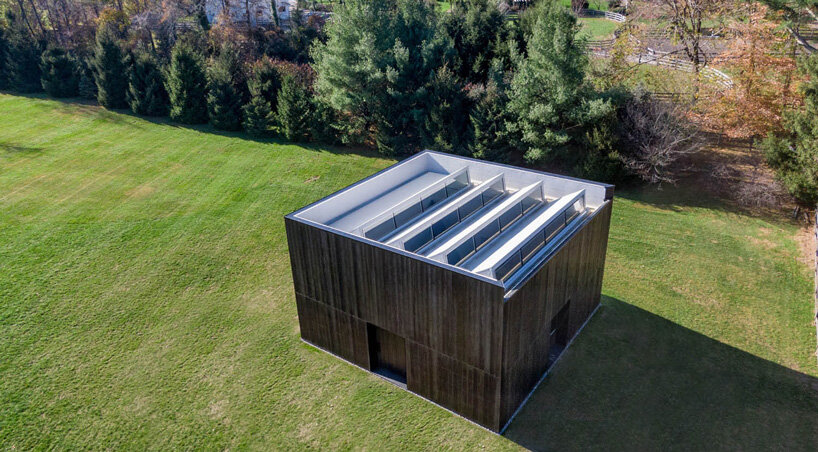 OLI architecture sets richard serra's london cross sculpture in charred wood pavilion in NY