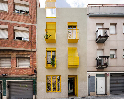 anna & eugeni bach punctuate 'seven lives' building in barcelona with yellow façade elements