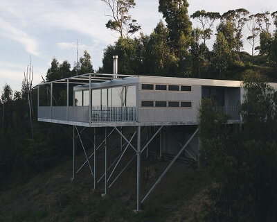 a minimalist weekend house projects out over a hillside in wye river, australia