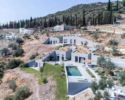 submerged volumes and planted roofs integrate these houses into the greek coastline