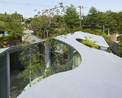 sculptural roof curves around growing trees in tomohiro hata's house in okuike, japan