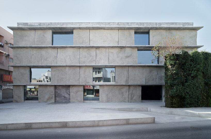sand-casted concrete façade clads the  green corner building by anne holtrop in bahrain