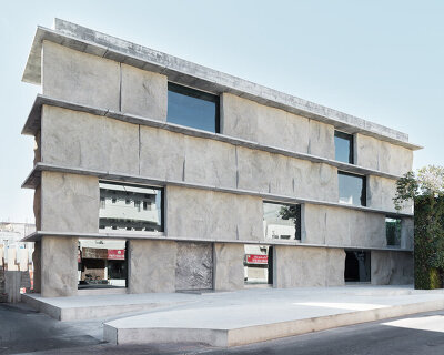 sand-casted concrete façade clads anne holtrop's green corner building in bahrain