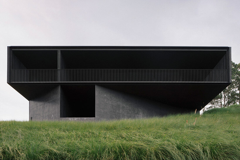 edition office anchors black concrete residence with strategic apertures to australian hilltop
