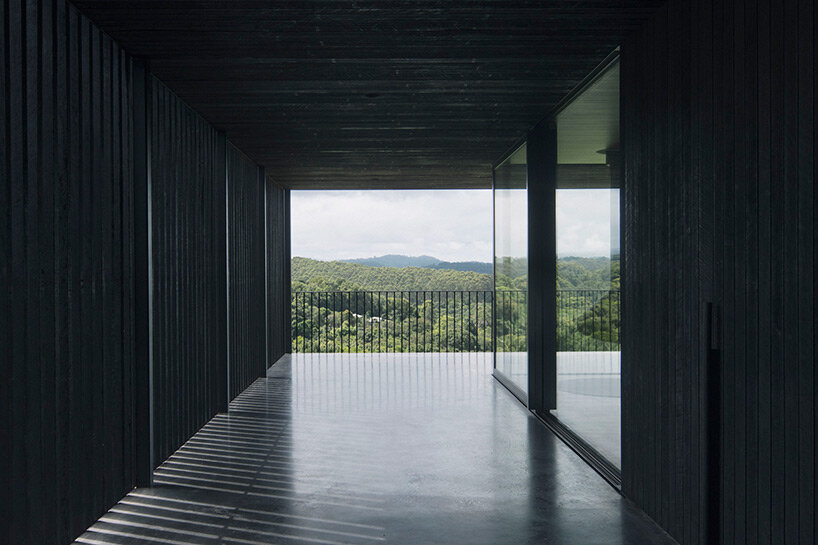 edition office anchors black concrete residence with strategic apertures to australian hilltop