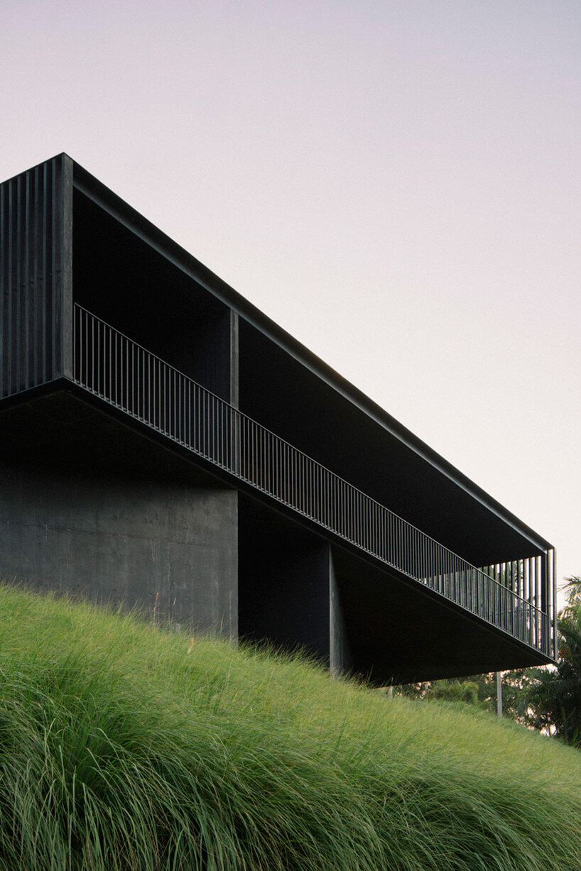 edition office anchors black concrete residence with strategic apertures to australian hilltop