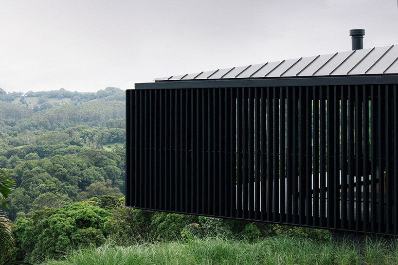 edition office anchors black concrete residence with strategic apertures to australian hilltop