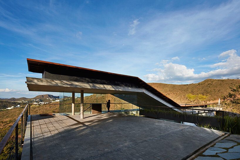 tetro tops residence with irregular deck roof opening towards mountainous views in brazil