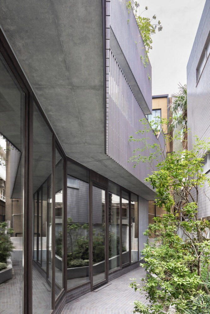 the linear façades around the building’s slab volumes are wrapped by metal bands with repetitive vertical slats