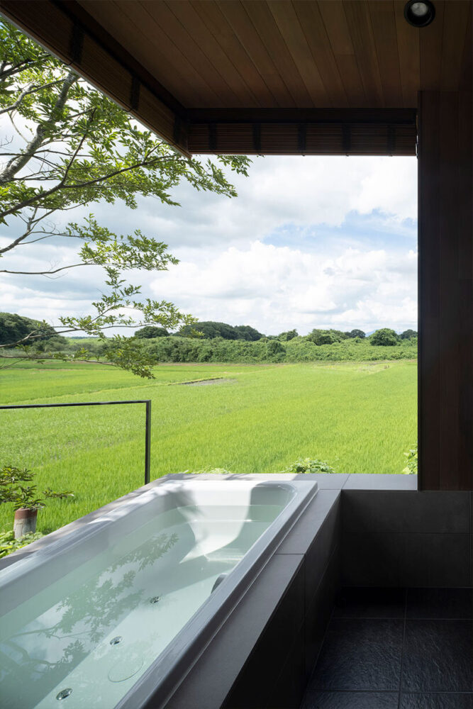 the elevated, open living space and balcony naturally draw the eye to the rice fields and forest visible in the distance