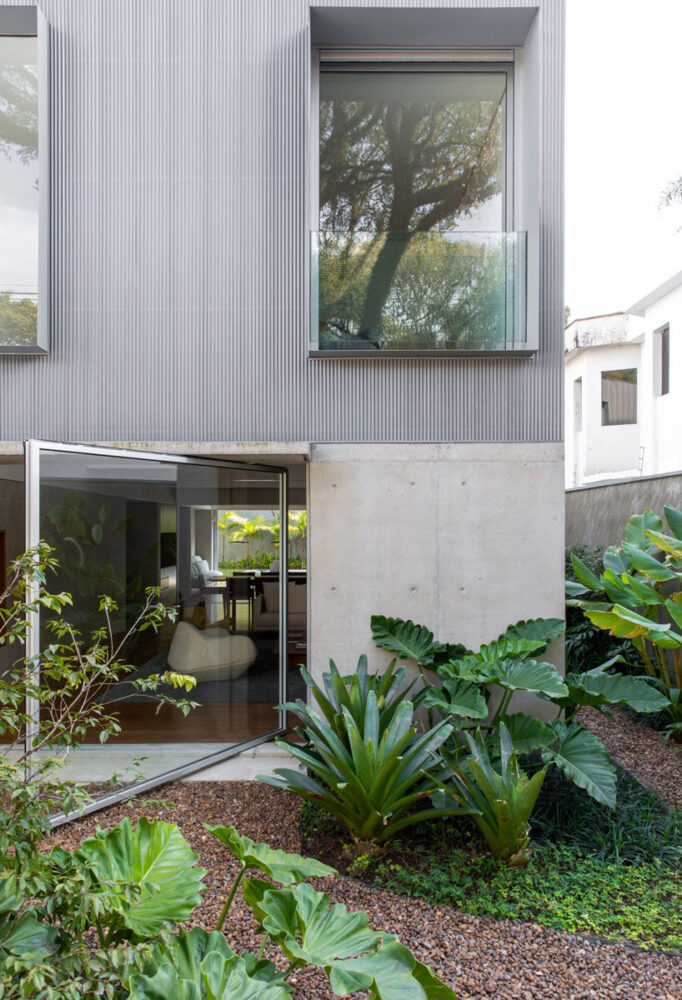 a glass pivot door blends house and garden for this são paulo residence
