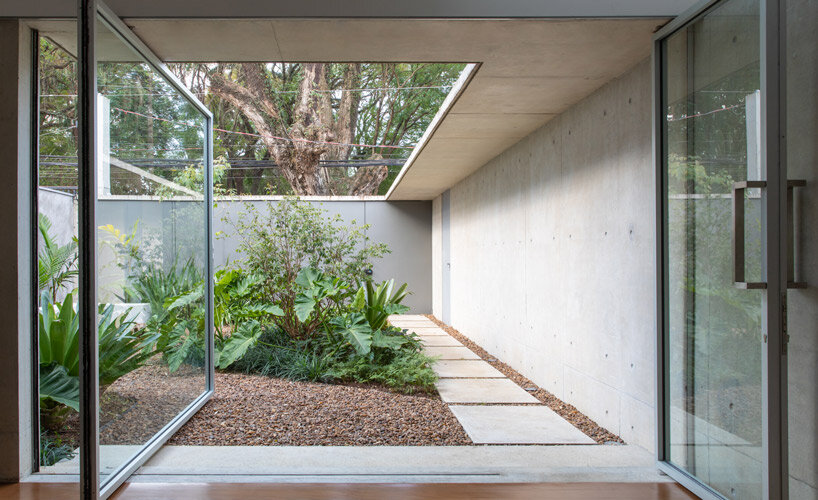 a glass pivot door blends house and garden for this são paulo residence