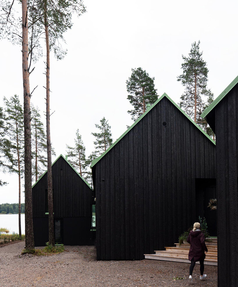 pirinen & salo sets three-volume charred wood house between pine trees in finland