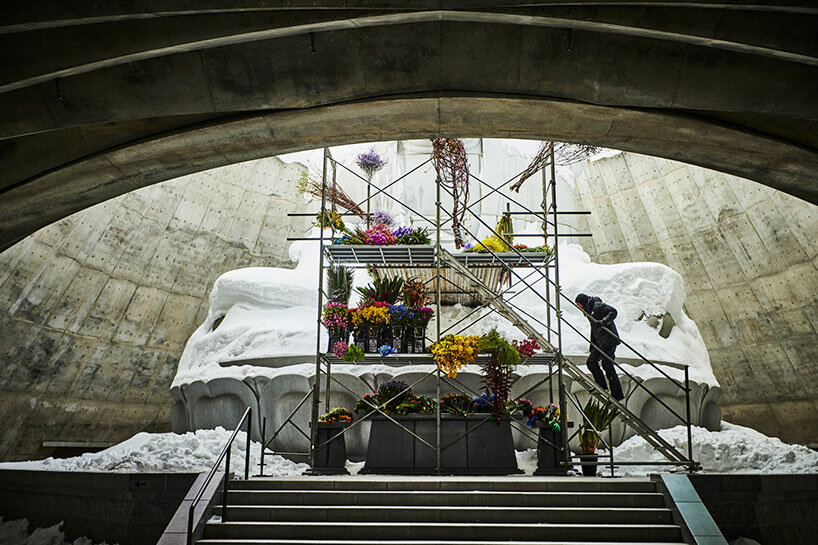beneath tadao ando’s hill, azuma makoto installs flower bouquet into arms of the buddha