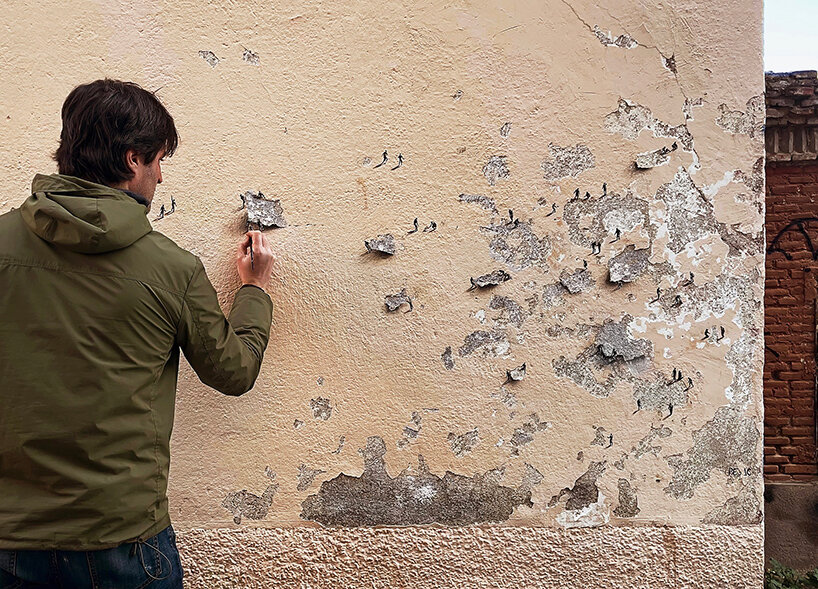tiny figures by urban artist pejac emerge from the cracks of peeling walls in madrid 