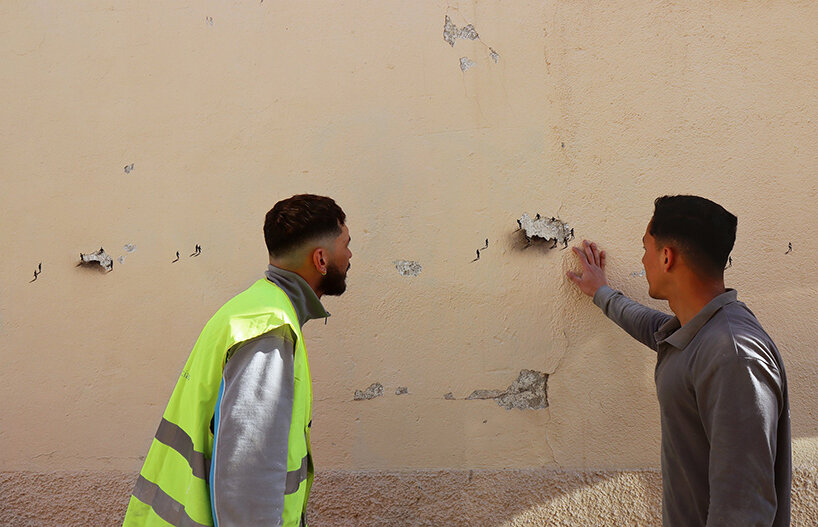 tiny figures by urban artist pejac emerge from the cracks of peeling walls in madrid 