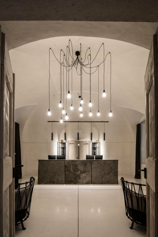 large stone reception desk covered with granite and illuminated by a ‘shower’ of minimalist hanging lamps