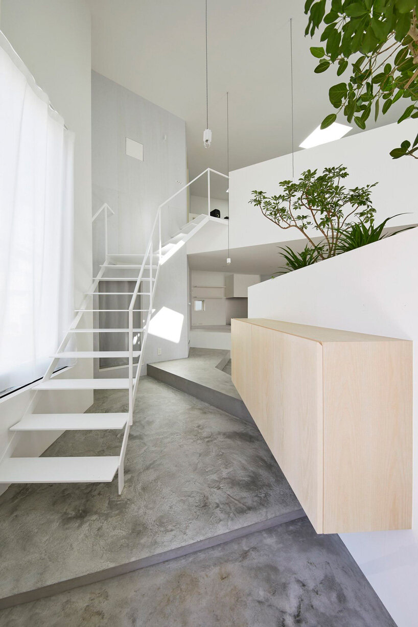 japanese residence by airhouse conceals minimalist interior of slanted floors and walls