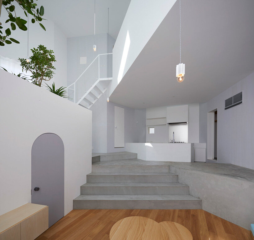 japanese residence by airhouse conceals minimalist interior of slanted floors and walls