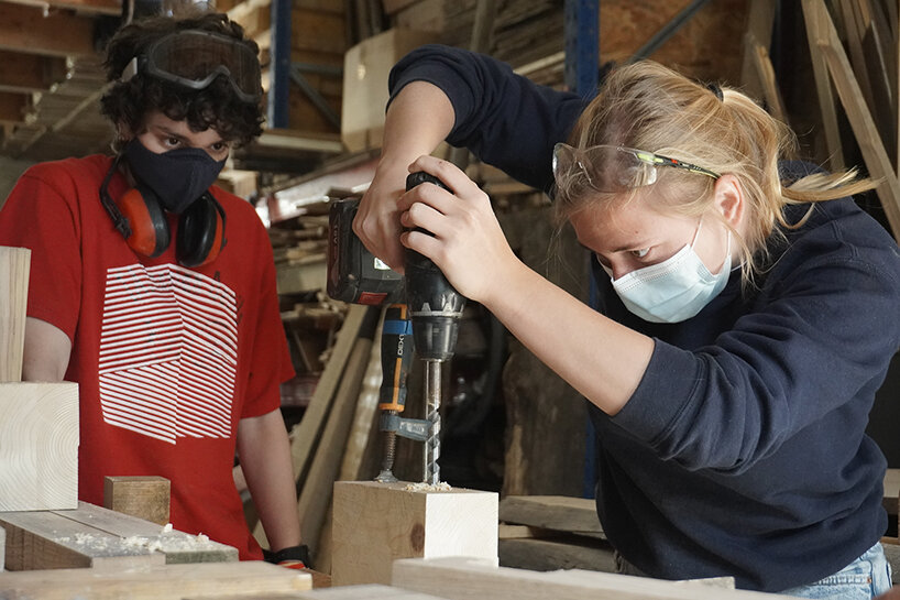 two students prepare a timber piece for a new facade structure