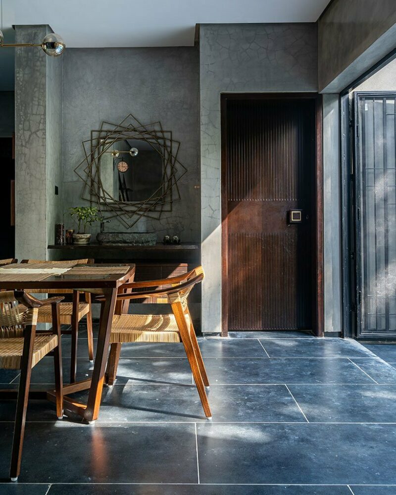 the artworks chosen for the house leans towards a rustic, earthy color palette The washbasin vanity set next to the dining area is in natural stone and was picked up from Auroville. the mirror is a bespoke piece crafted from metal