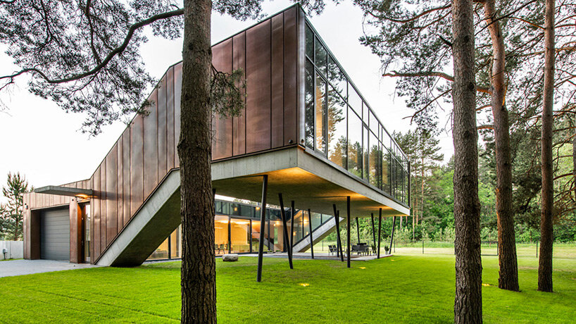 copper-clad zigzag house by g.natkevicius & partners hovers above pine forest in lithuania