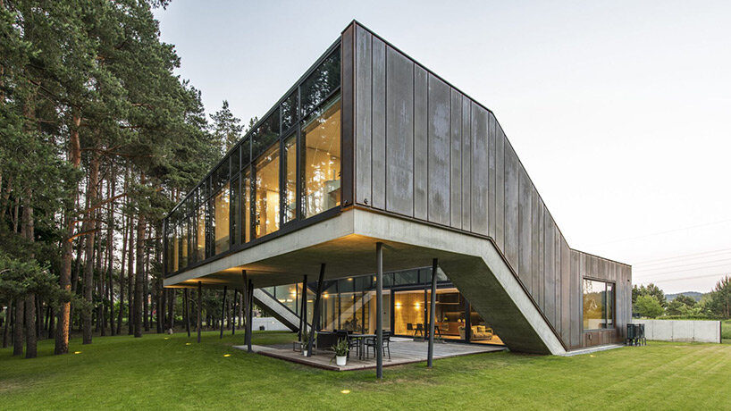 copper-clad zigzag house by g.natkevicius & partners hovers above pine forest in lithuania