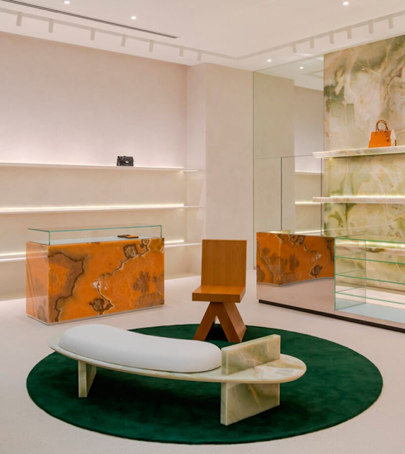 a long curved bench fabricated out of green onyx and an oak armchair frame the waiting area