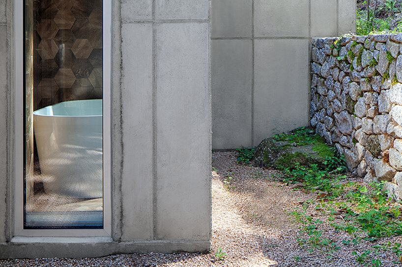 a minimalist retreat is nestled beneath the wooded mountains of korea