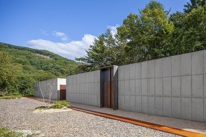 a minimalist retreat is nestled beneath the wooded mountains of korea