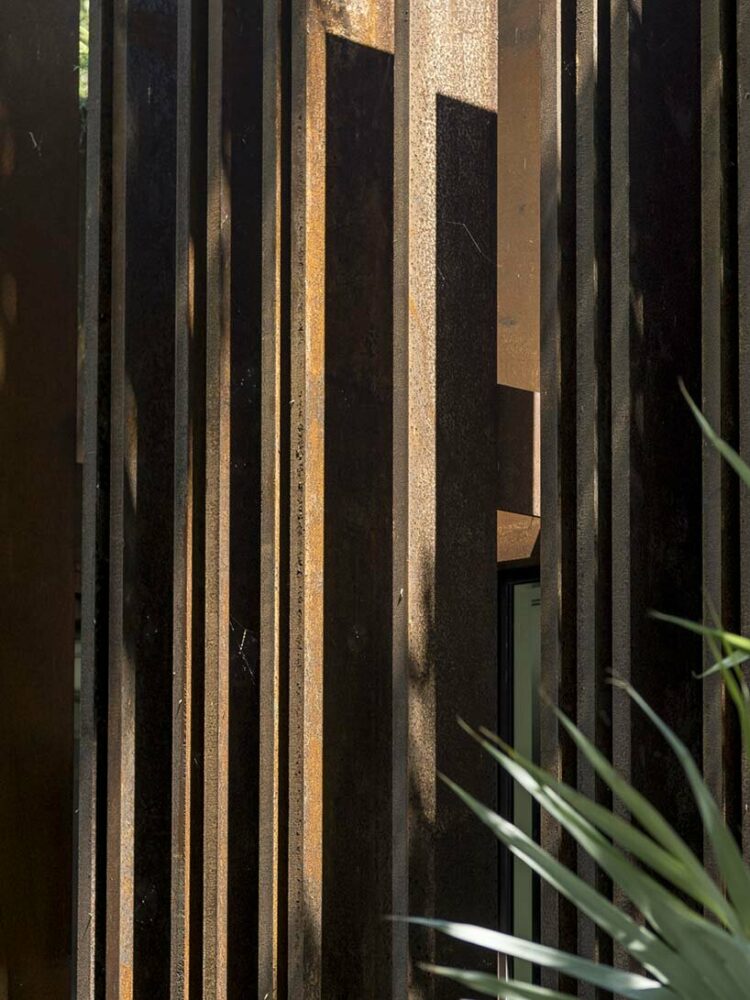 a corten steel gatehouse is overgrown by tropical nature in coconut grove, miami