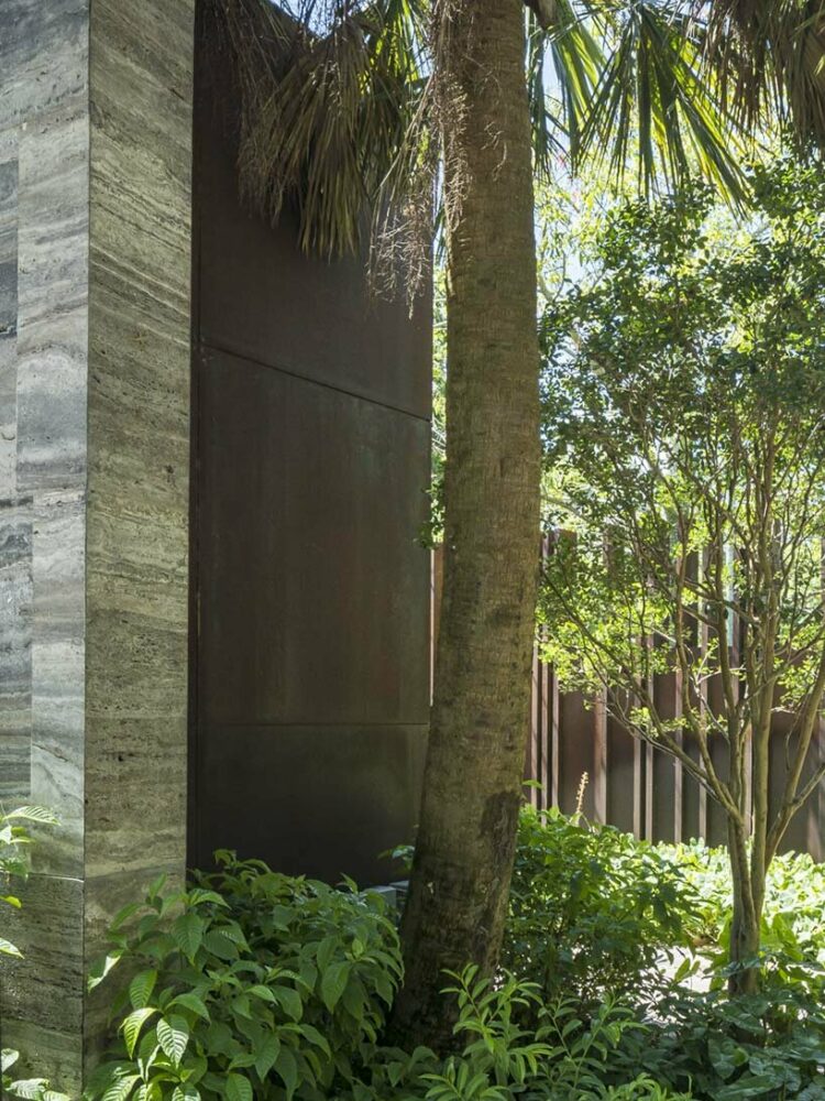 a corten steel gatehouse is overgrown by tropical nature in coconut grove, miami