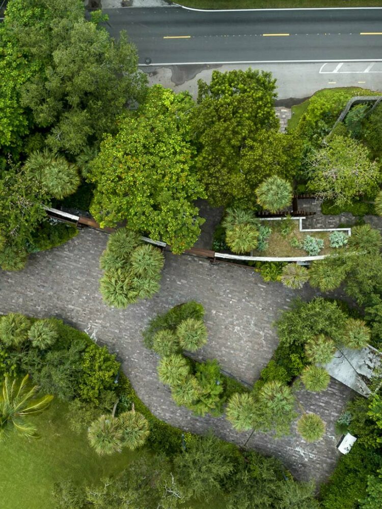 a corten steel gatehouse is overgrown by tropical nature in coconut grove, miami